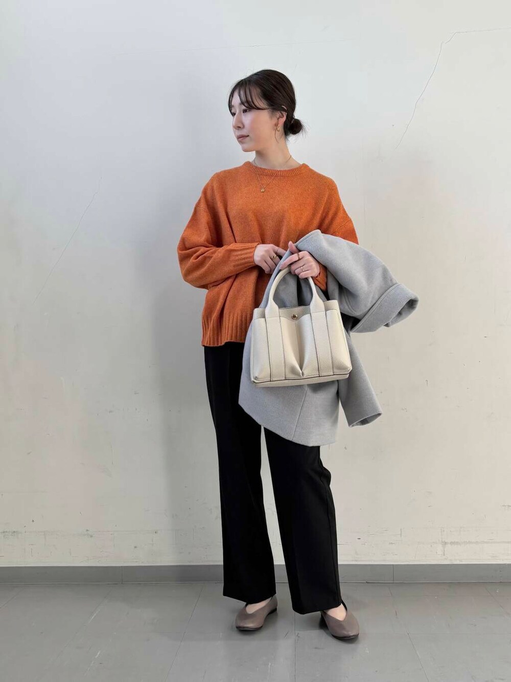 ベージュ系のパンプス、オレンジ系のニット/セーター、グレー系のステンカラーコートを着用したレディースの冬コーディネートの4枚目の写真