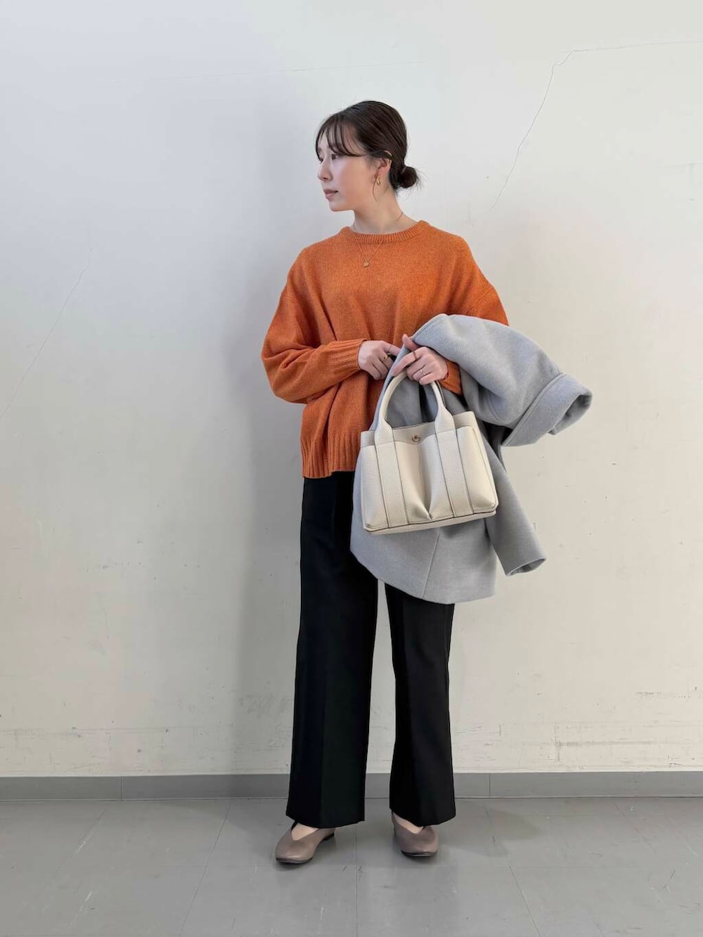 ベージュ系のパンプス、オレンジ系のニット/セーター、グレー系のステンカラーコートを着用したレディースの冬コーディネートの5枚目の写真
