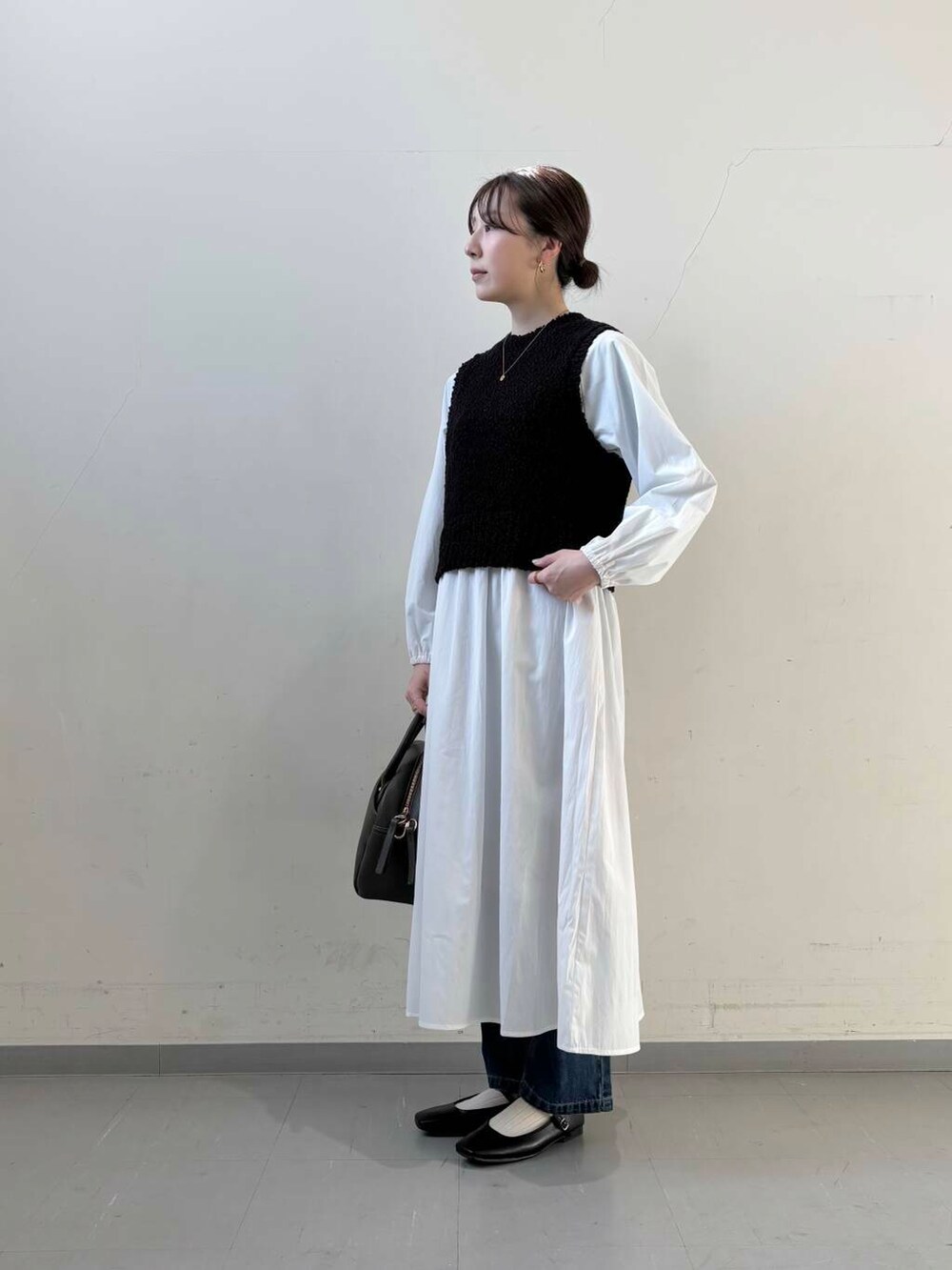 ブルー系のデニムパンツ、ブラック系のボストンバッグ、ブラック系のパンプスを着用したレディースの冬コーディネートの3枚目の写真