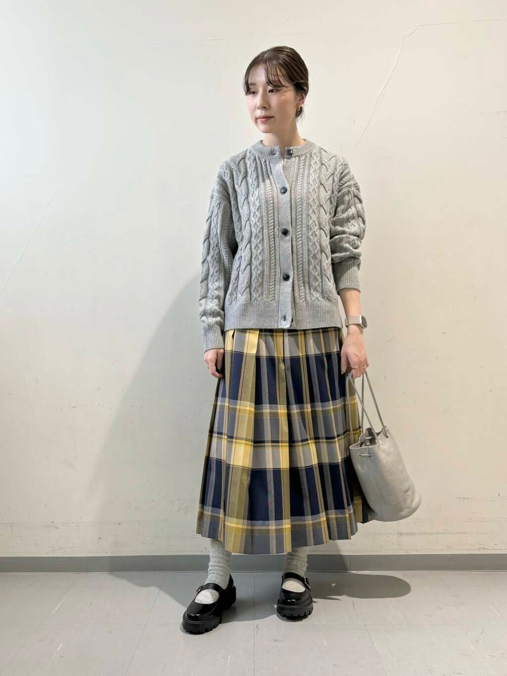 グレー系のカーディガン/ボレロ、グレー系のショルダーバッグ、ブルー系のスカートを着用したレディースの秋コーディネートの4枚目の写真
