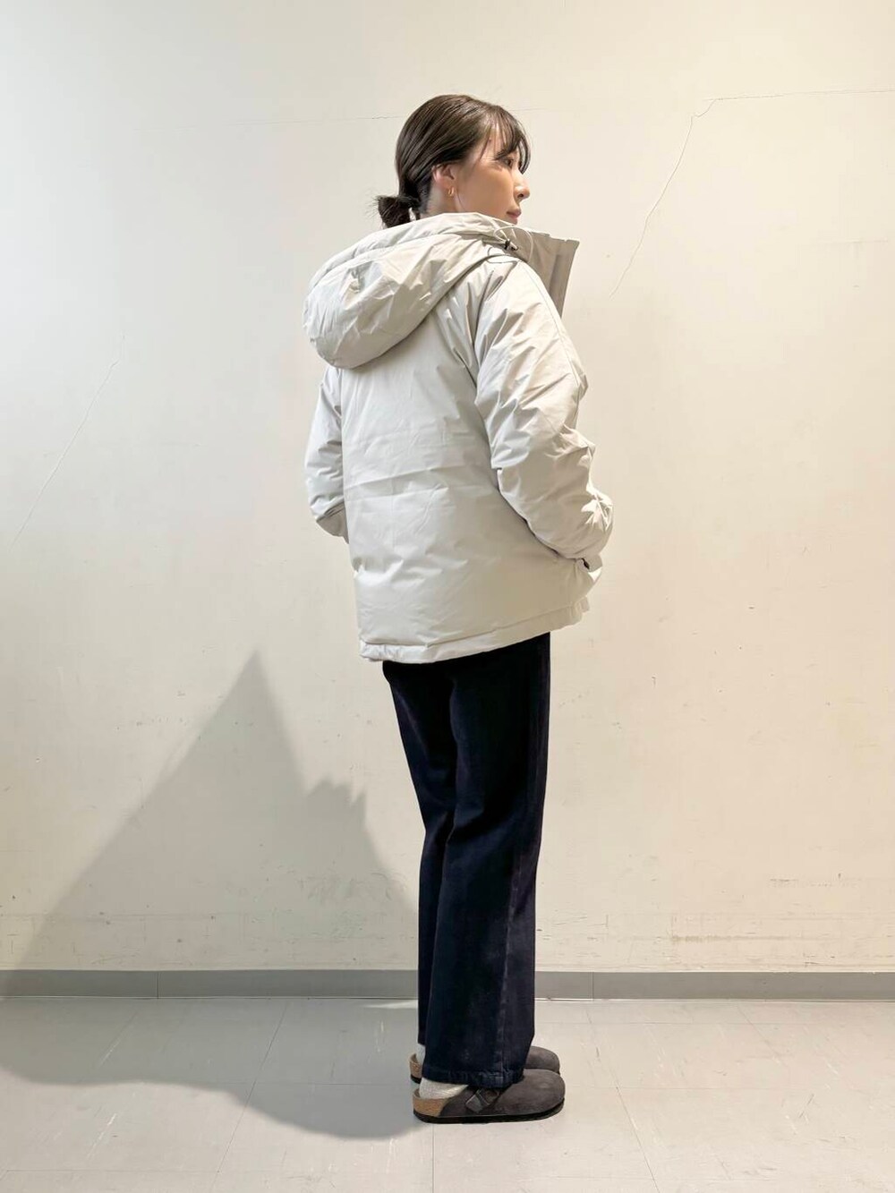 ブルー系のデニムパンツ、パープル系のニット/セーター、ホワイト系のダウンジャケット/コートを着用したレディースの秋コーディネートの3枚目の写真