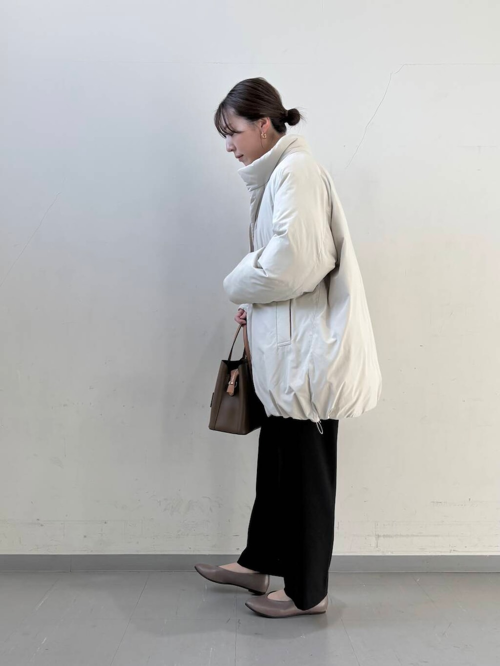 ベージュ系のパンプス、ブラウン系のハンドバッグ、ベージュ系のニット/セーターを着用したレディースの冬コーディネートの4枚目の写真