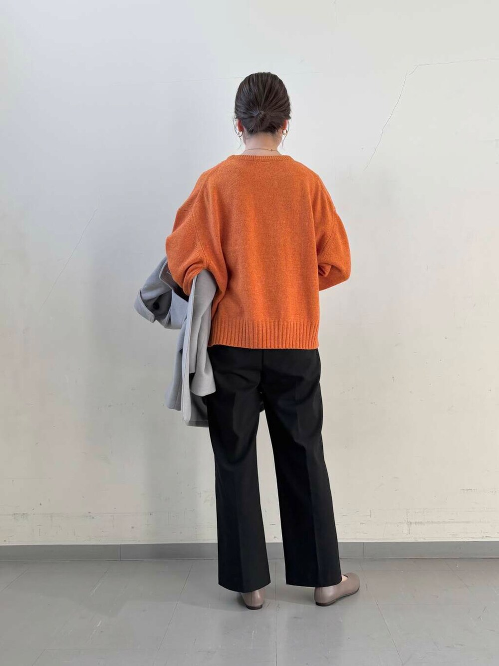 ベージュ系のパンプス、オレンジ系のニット/セーター、グレー系のステンカラーコートを着用したレディースの冬コーディネートの6枚目の写真