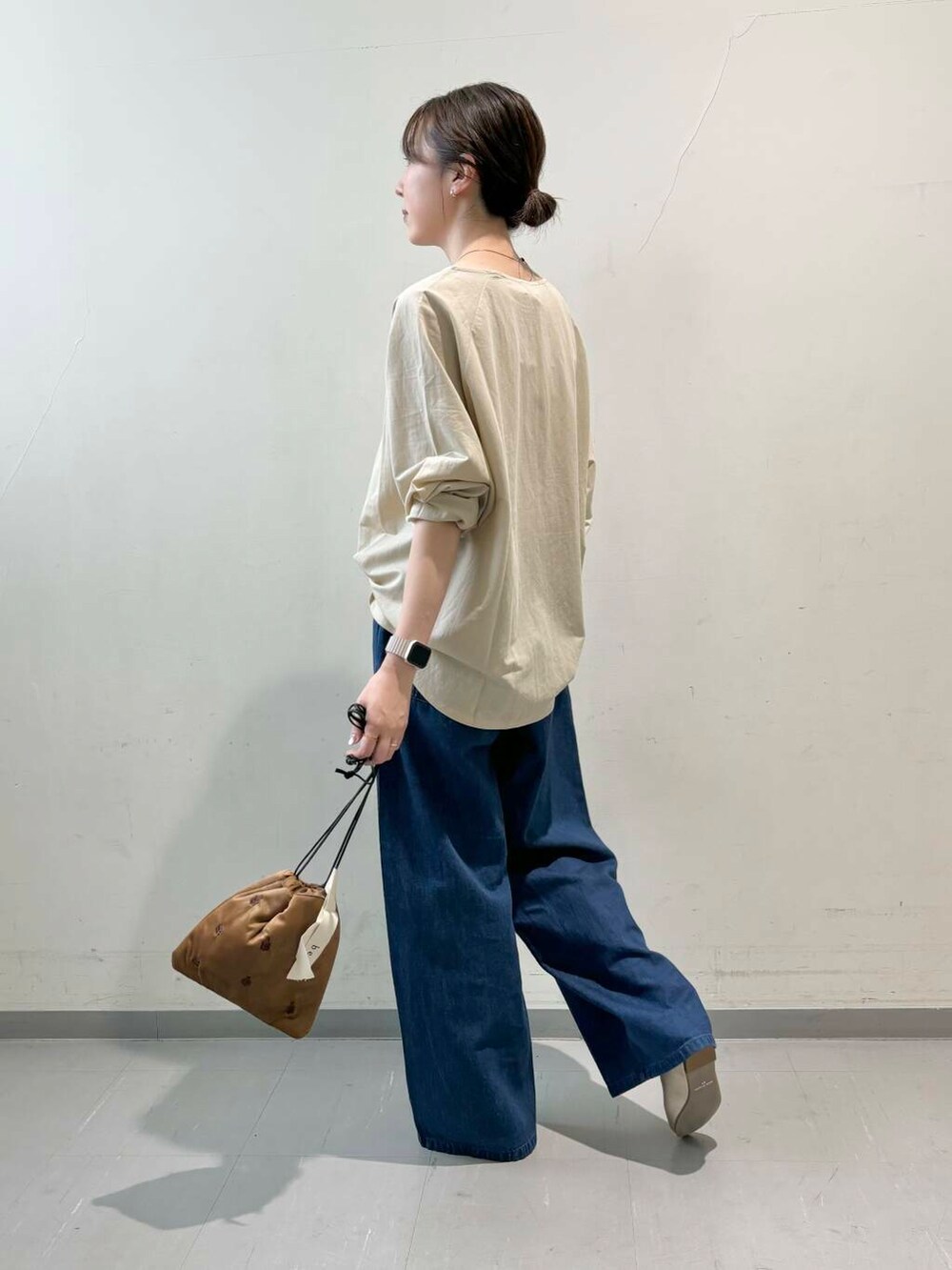 ゴールド系のパンプス、ブラウン系のショルダーバッグ、ブルー系のデニムパンツを着用したレディースの夏コーディネートの2枚目の写真