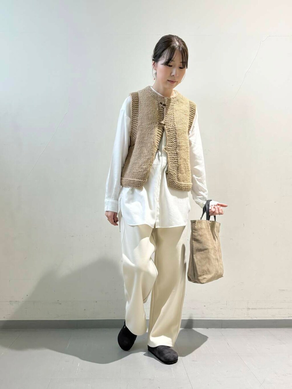 ベージュ系のトートバッグ、ブラウン系のベスト、ホワイト系のシャツ/ブラウスを着用したレディースの秋コーディネートの3枚目の写真