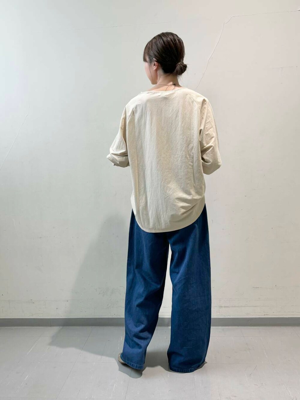 ゴールド系のパンプス、ブラウン系のショルダーバッグ、ブルー系のデニムパンツを着用したレディースの夏コーディネートの3枚目の写真