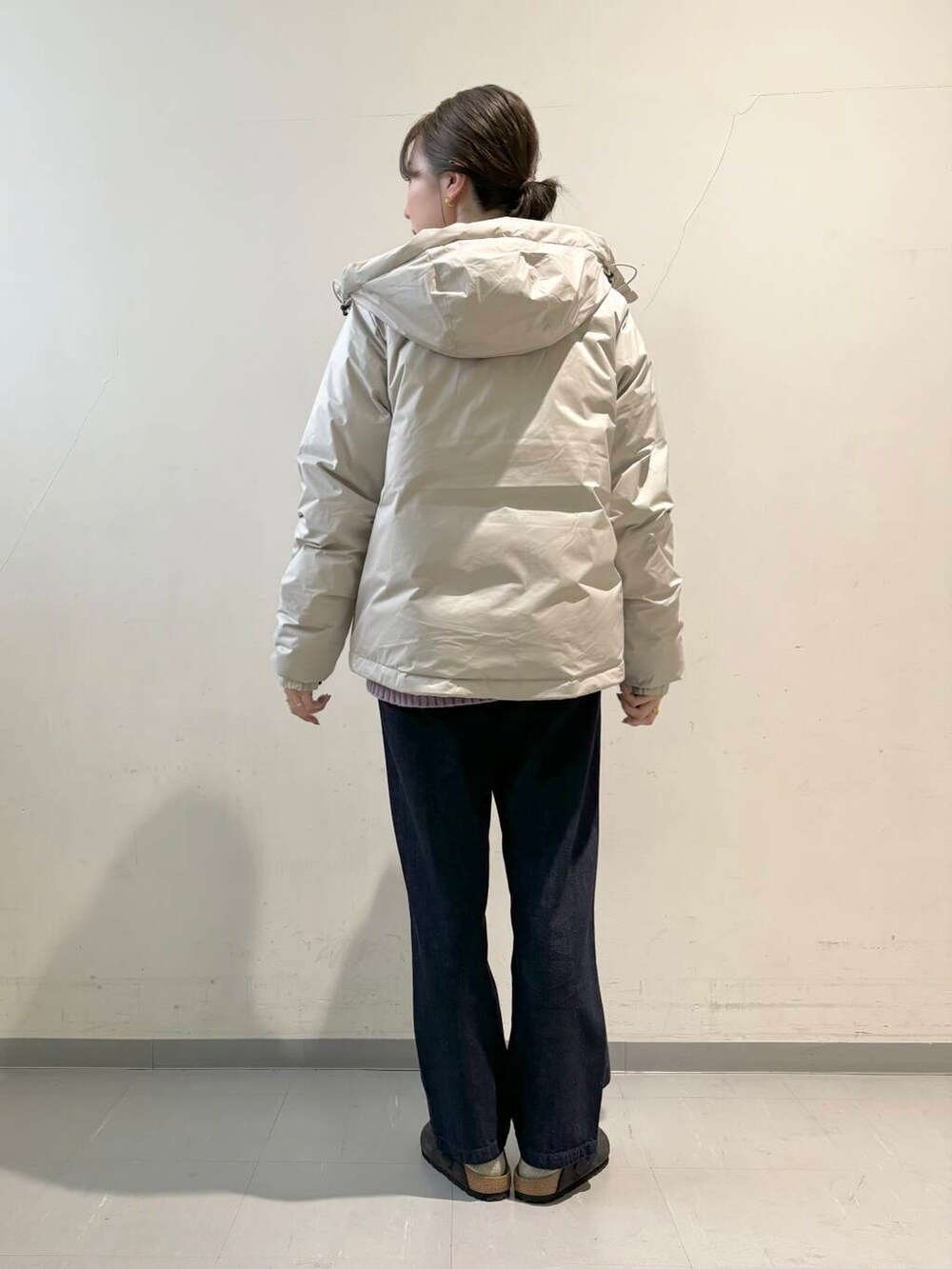 ブルー系のデニムパンツ、パープル系のニット/セーター、ホワイト系のダウンジャケット/コートを着用したレディースの秋コーディネートの4枚目の写真
