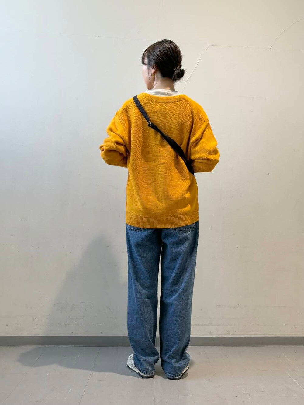 ブルー系のデニムパンツ、ホワイト系のスニーカー、イエロー系のカーディガン/ボレロを着用したレディースの秋コーディネートの3枚目の写真