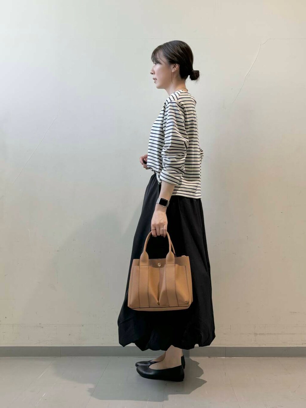 ベージュ系のトートバッグ、ブラック系のパンプス、ブラック系のスカートを着用したレディースの秋コーディネートの2枚目の写真