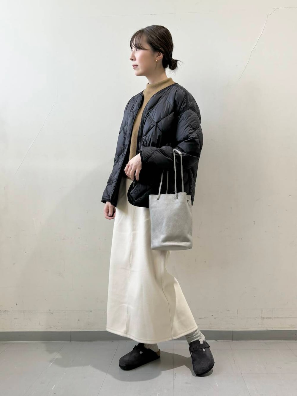 ブラック系のダウンジャケット/コート、グレー系のショルダーバッグ、グリーン系のニット/セーターを着用したレディースの秋コーディネートの2枚目の写真