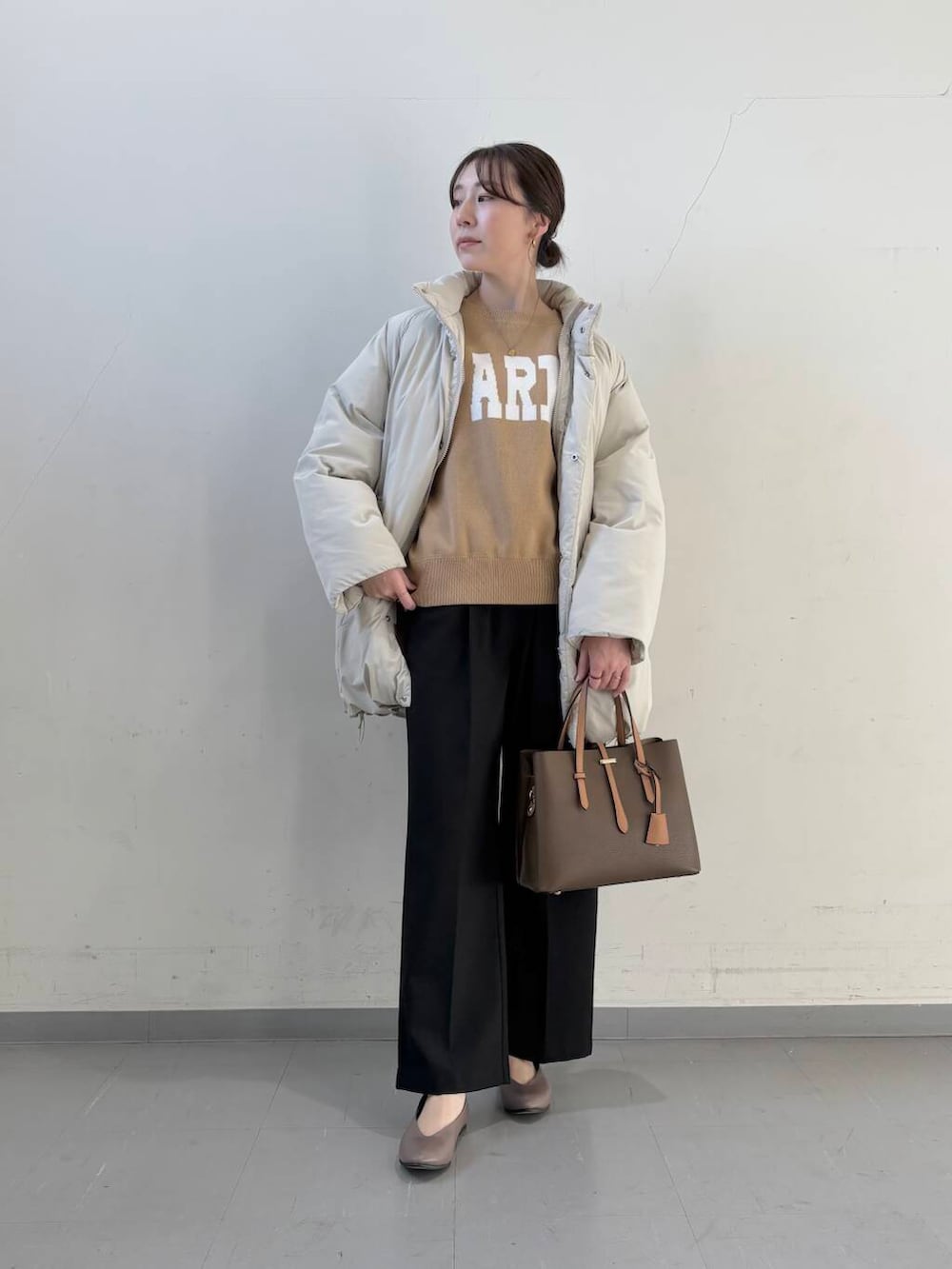 ベージュ系のパンプス、ブラウン系のハンドバッグ、ベージュ系のニット/セーターを着用したレディースの冬コーディネートの3枚目の写真