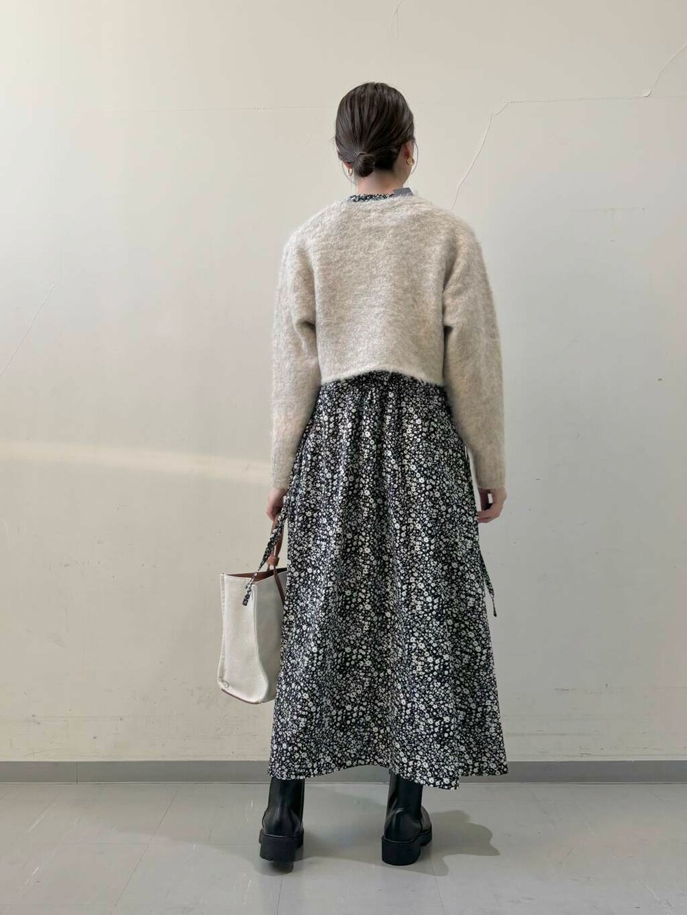 ブラック系のブーツ、ベージュ系のトートバッグ、ブラック系のワンピースを着用したレディースの秋コーディネートの4枚目の写真