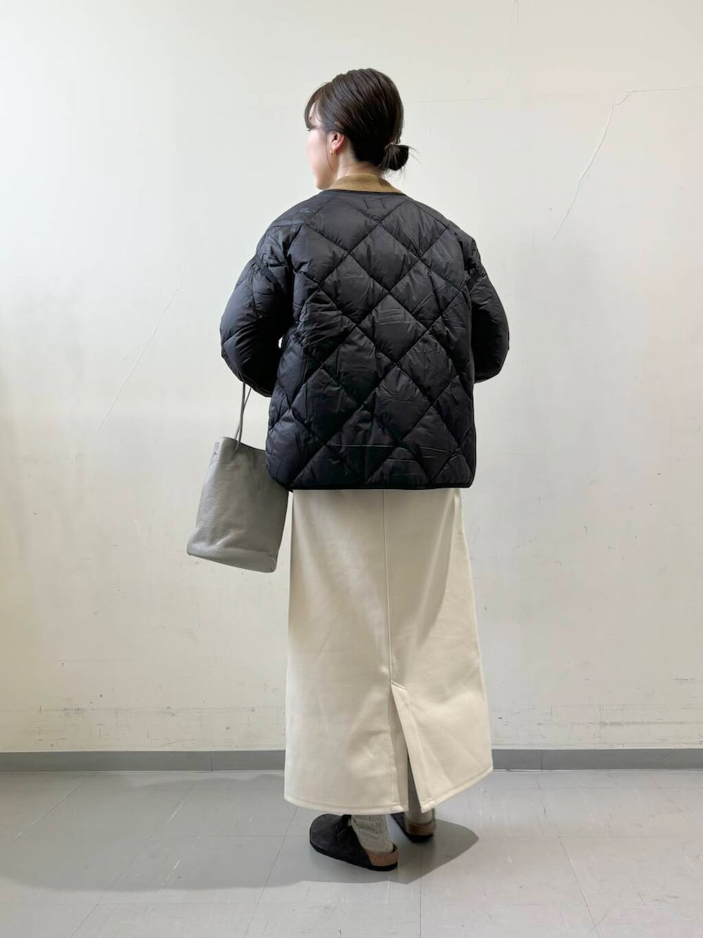 ブラック系のダウンジャケット/コート、グレー系のショルダーバッグ、グリーン系のニット/セーターを着用したレディースの秋コーディネートの3枚目の写真