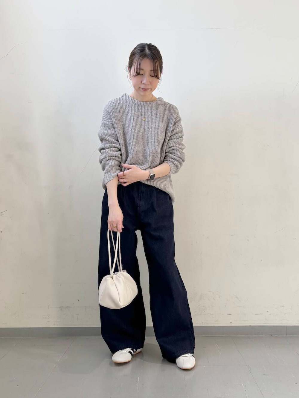ブルー系のデニムパンツ、ホワイト系のショルダーバッグ、グレー系のニット/セーターを着用したレディースの春コーディネートの2枚目の写真