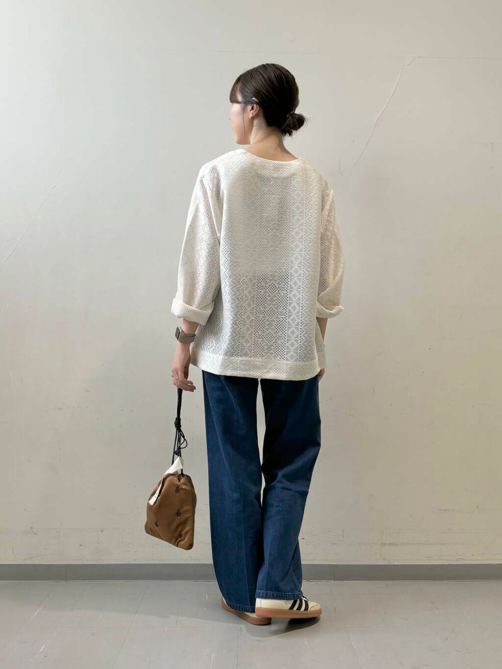 ホワイト系のタンクトップ、ブラウン系のショルダーバッグ、ベージュ系のスニーカーを着用したレディースの夏コーディネートの3枚目の写真