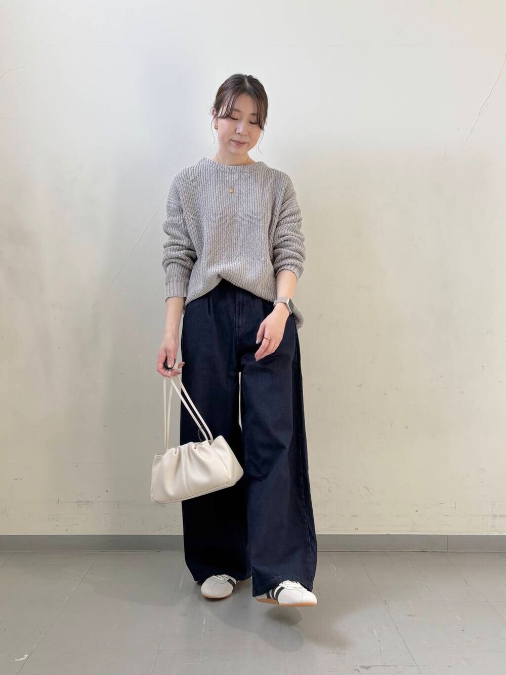 ブルー系のデニムパンツ、ホワイト系のショルダーバッグ、グレー系のニット/セーターを着用したレディースの春コーディネートの3枚目の写真
