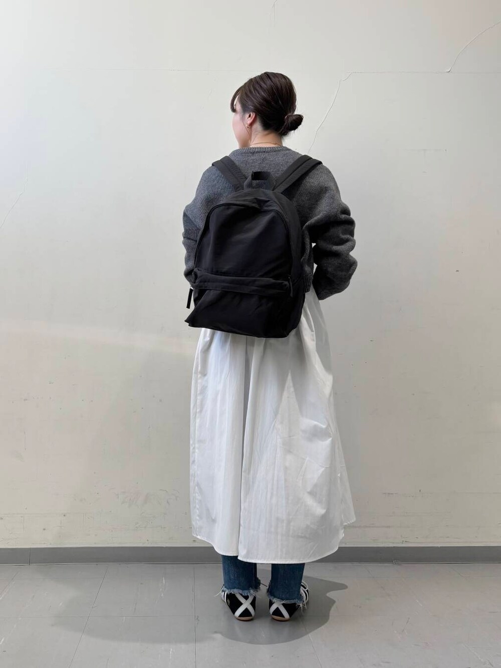 ブラック系のバックパック/リュック、グレー系のニット/セーター、グレー系のワンピースを着用したレディースの冬コーディネートの5枚目の写真