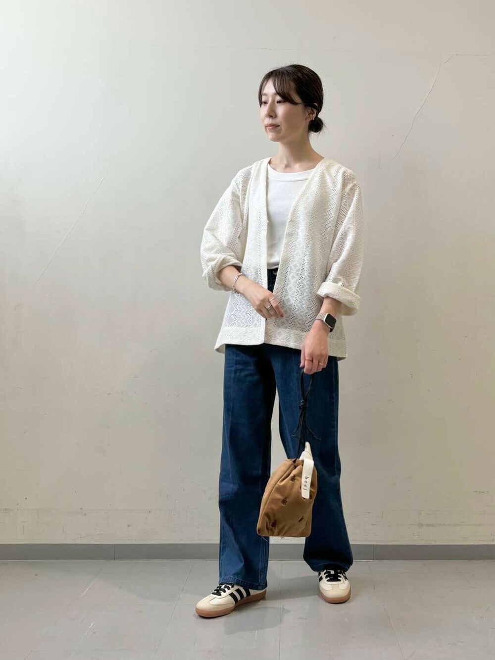 ホワイト系のタンクトップ、ブラウン系のショルダーバッグ、ベージュ系のスニーカーを着用したレディースの夏コーディネートの2枚目の写真