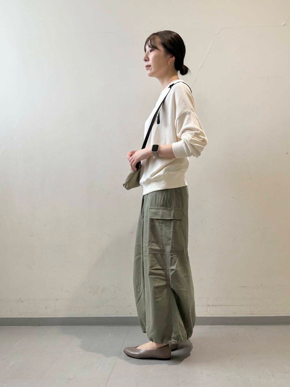 ベージュ系のパンプス、ベージュ系のTシャツ/カットソー、グリーン系のスカートを着用したレディースの秋コーディネートの8枚目の写真