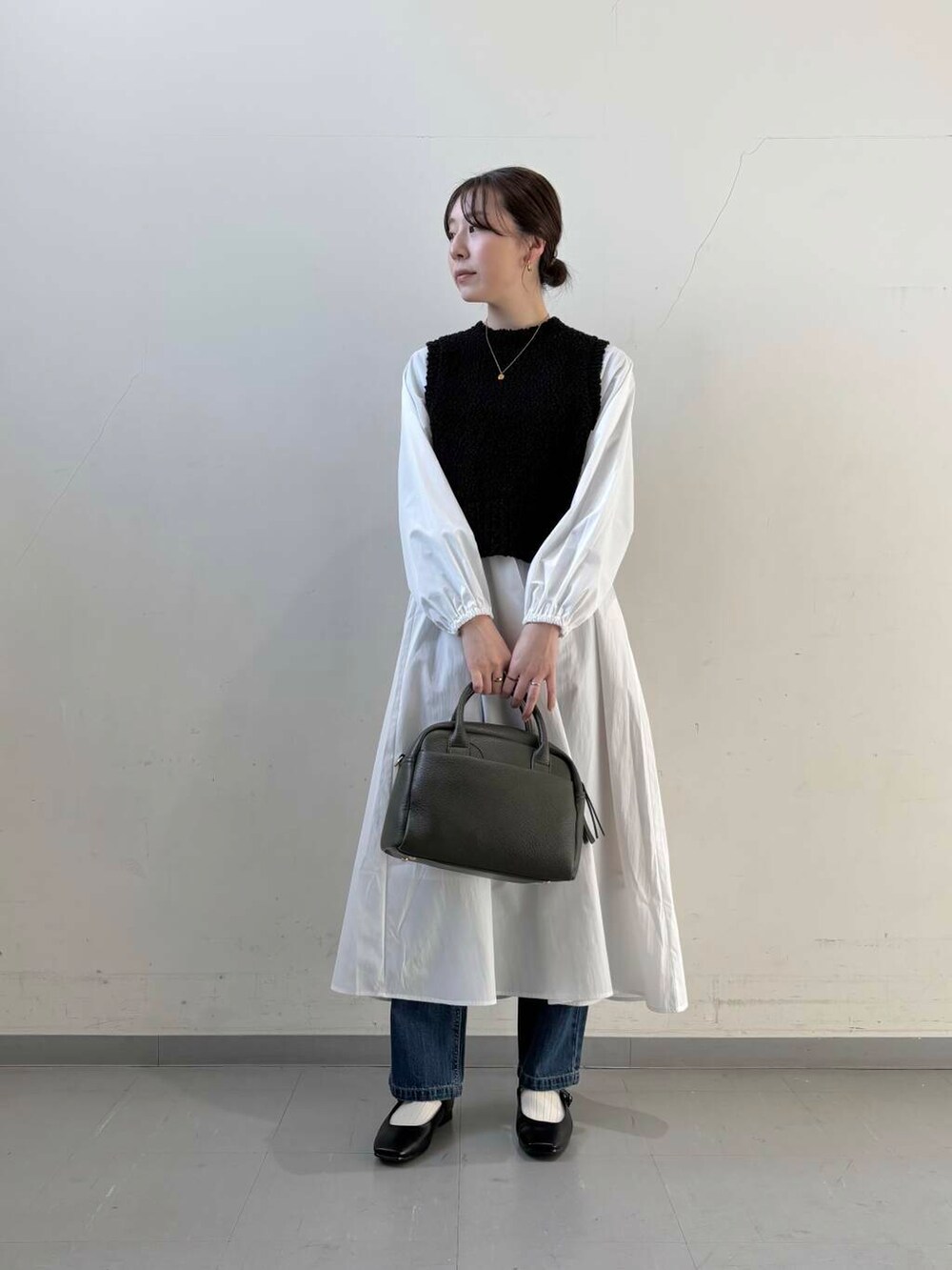 ブルー系のデニムパンツ、ブラック系のボストンバッグ、ブラック系のパンプスを着用したレディースの冬コーディネートの2枚目の写真
