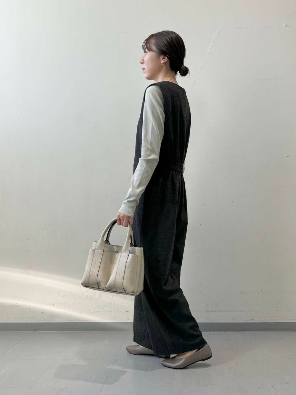 ホワイト系のトートバッグ、ベージュ系のパンプス、グレー系のTシャツ/カットソーを着用したレディースの秋コーディネートの4枚目の写真