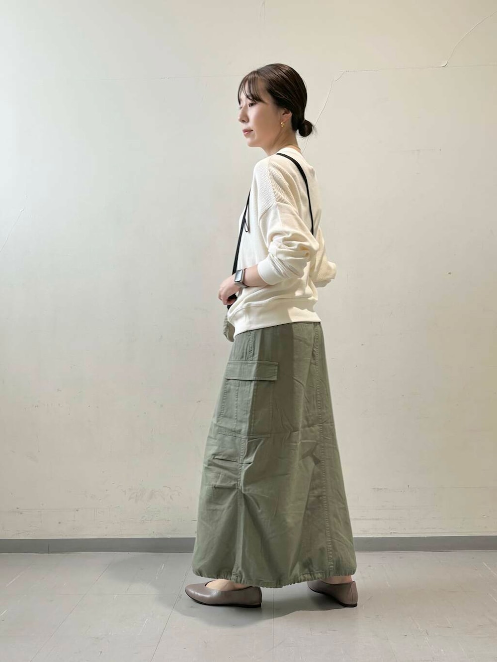 ベージュ系のパンプス、ベージュ系のTシャツ/カットソー、グリーン系のスカートを着用したレディースの秋コーディネートの6枚目の写真