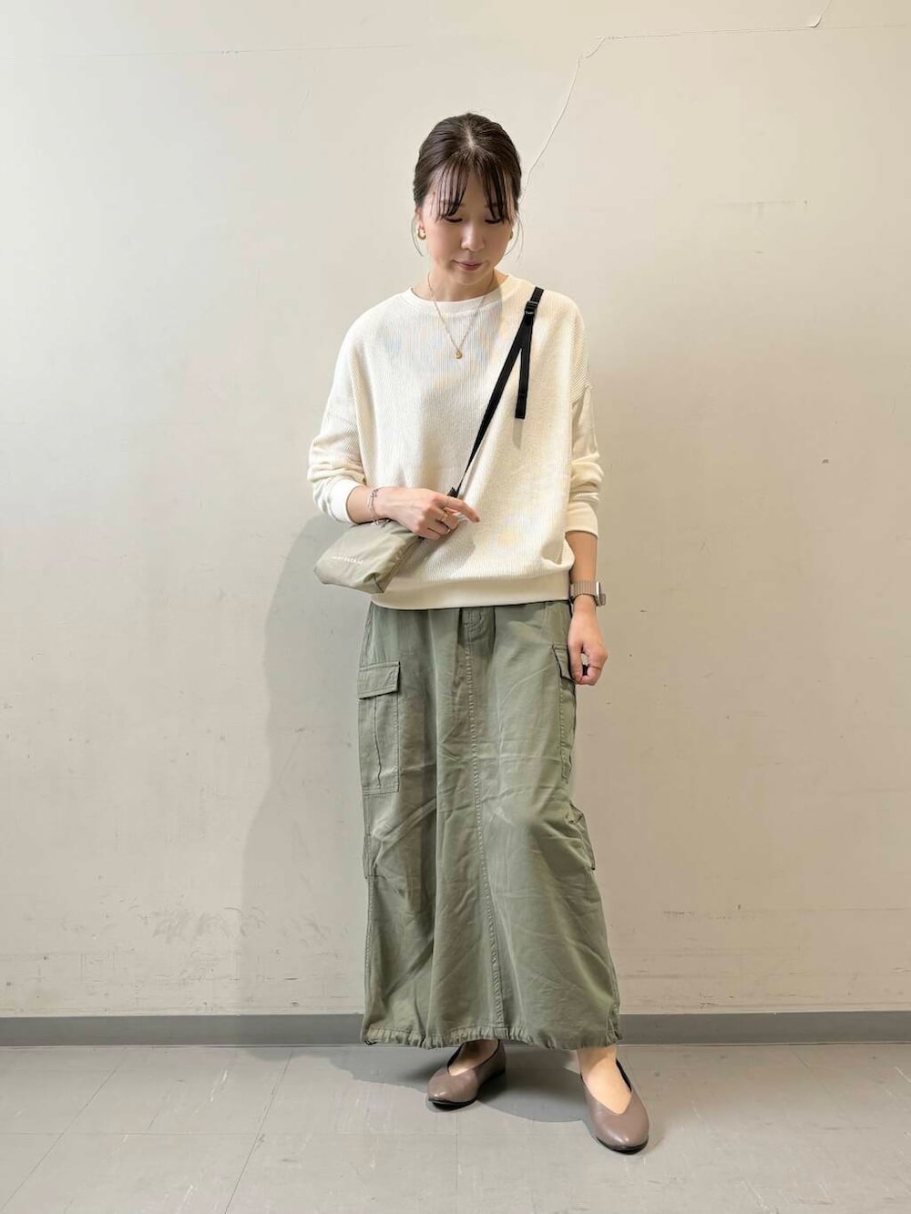 ベージュ系のパンプス、ベージュ系のTシャツ/カットソー、グリーン系のスカートを着用したレディースの秋コーディネートの4枚目の写真