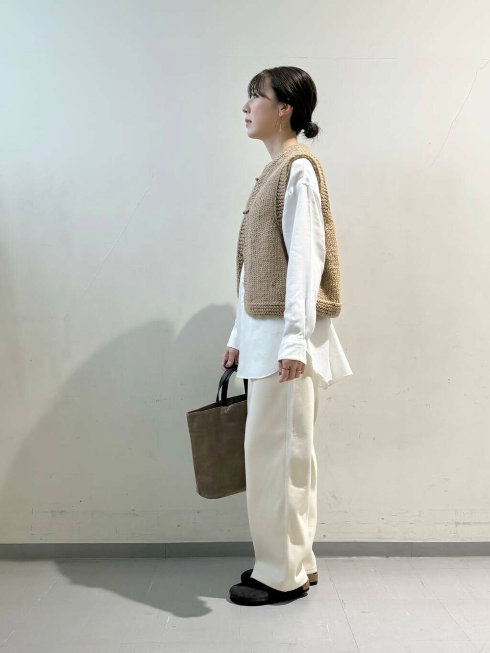 ベージュ系のトートバッグ、ブラウン系のベスト、ホワイト系のシャツ/ブラウスを着用したレディースの秋コーディネートの4枚目の写真