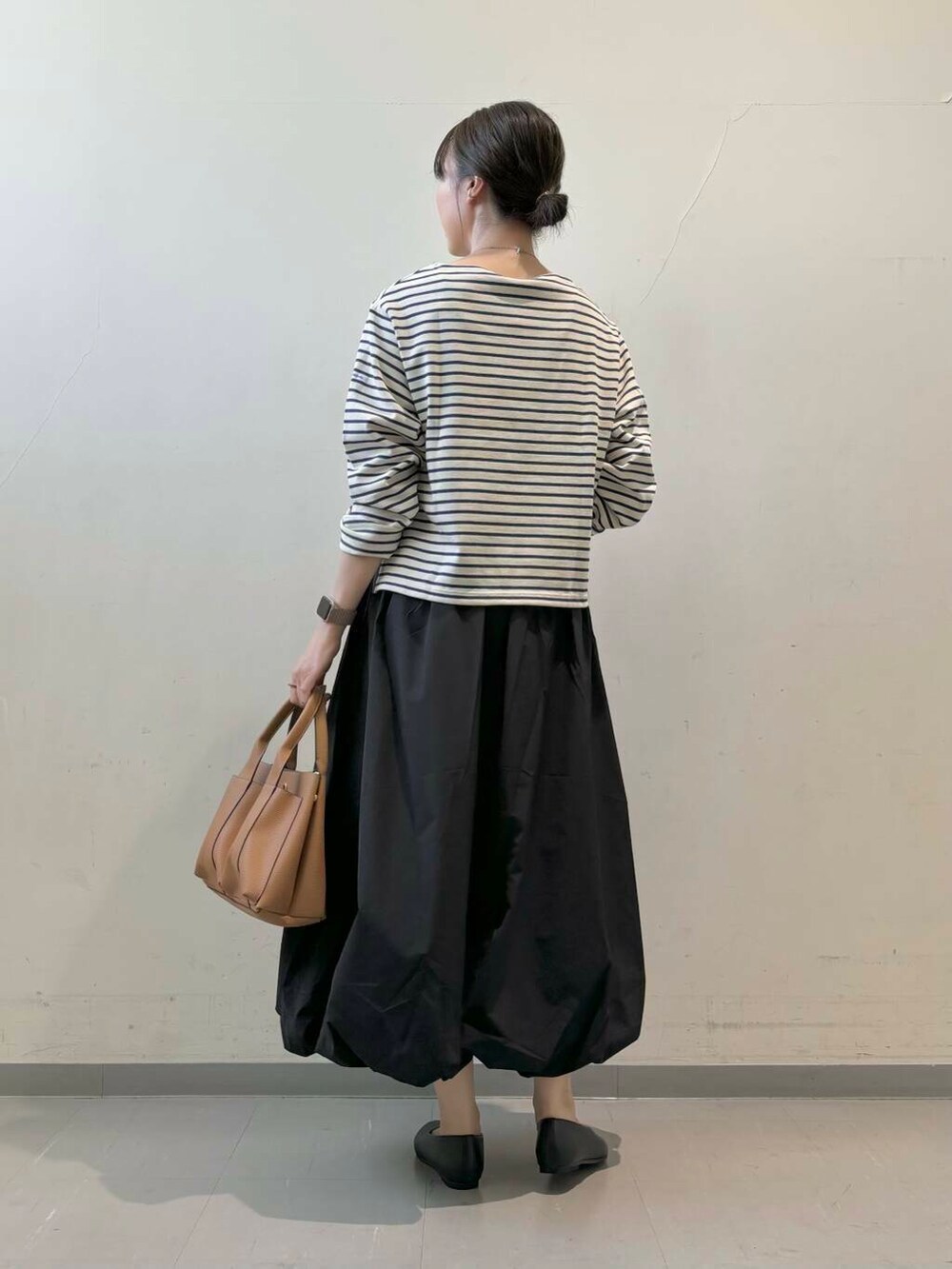 ベージュ系のトートバッグ、ブラック系のパンプス、ブラック系のスカートを着用したレディースの秋コーディネートの4枚目の写真