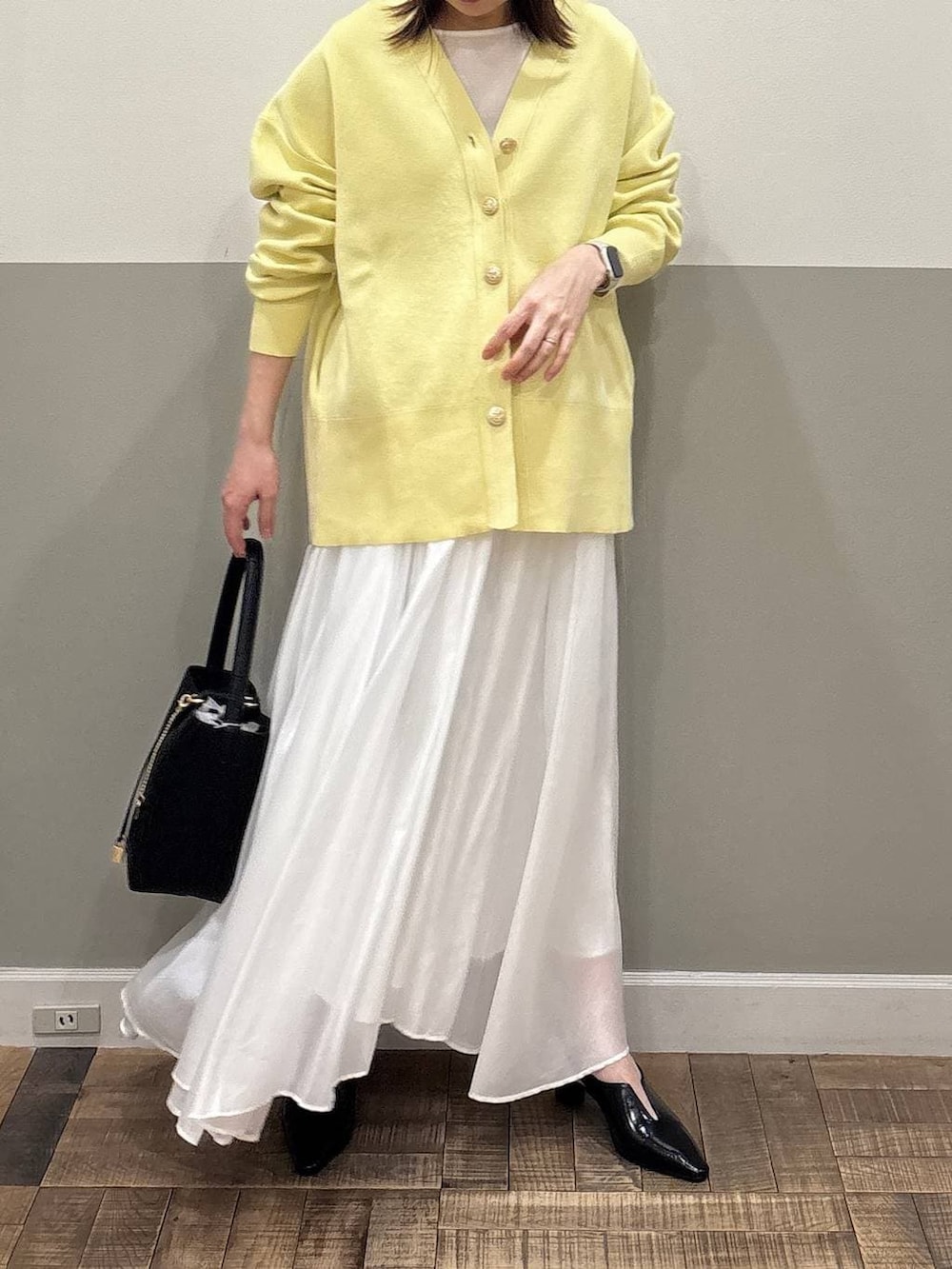 イエロー系のカーディガン/ボレロ、ホワイト系のスカート、ブラック系のその他シューズを着用したレディースの冬コーディネートの2枚目の写真