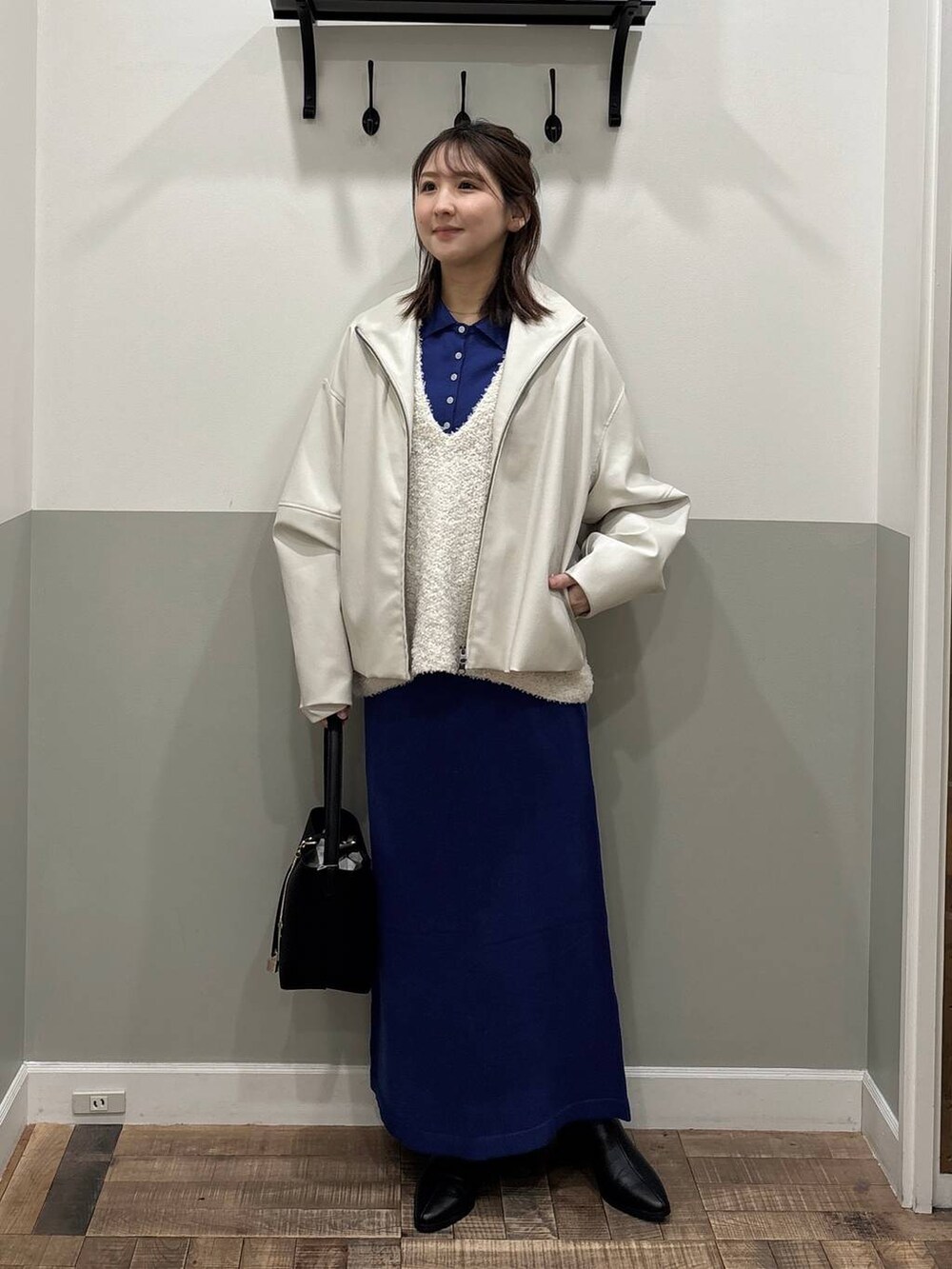 ブラック系のブーツ、ブルー系のワンピース、ホワイト系のブルゾンを着用したレディースの冬コーディネートの2枚目の写真