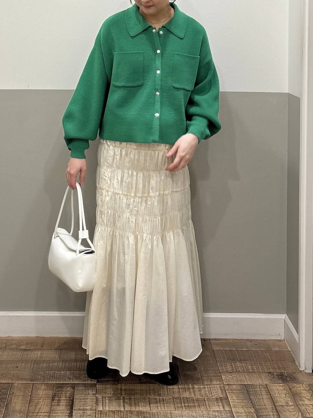 ブラウン系のローファー、ホワイト系のショルダーバッグ、グリーン系のカーディガン/ボレロを着用したレディースの冬コーディネートの2枚目の写真