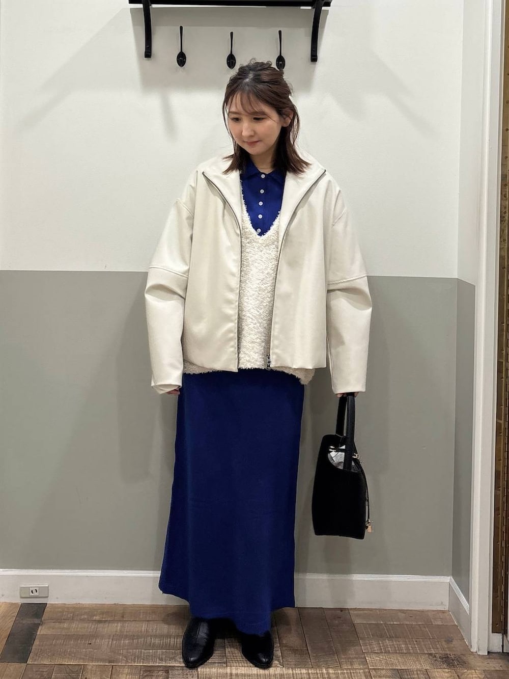 ブラック系のブーツ、ブルー系のワンピース、ホワイト系のブルゾンを着用したレディースの冬コーディネートの3枚目の写真