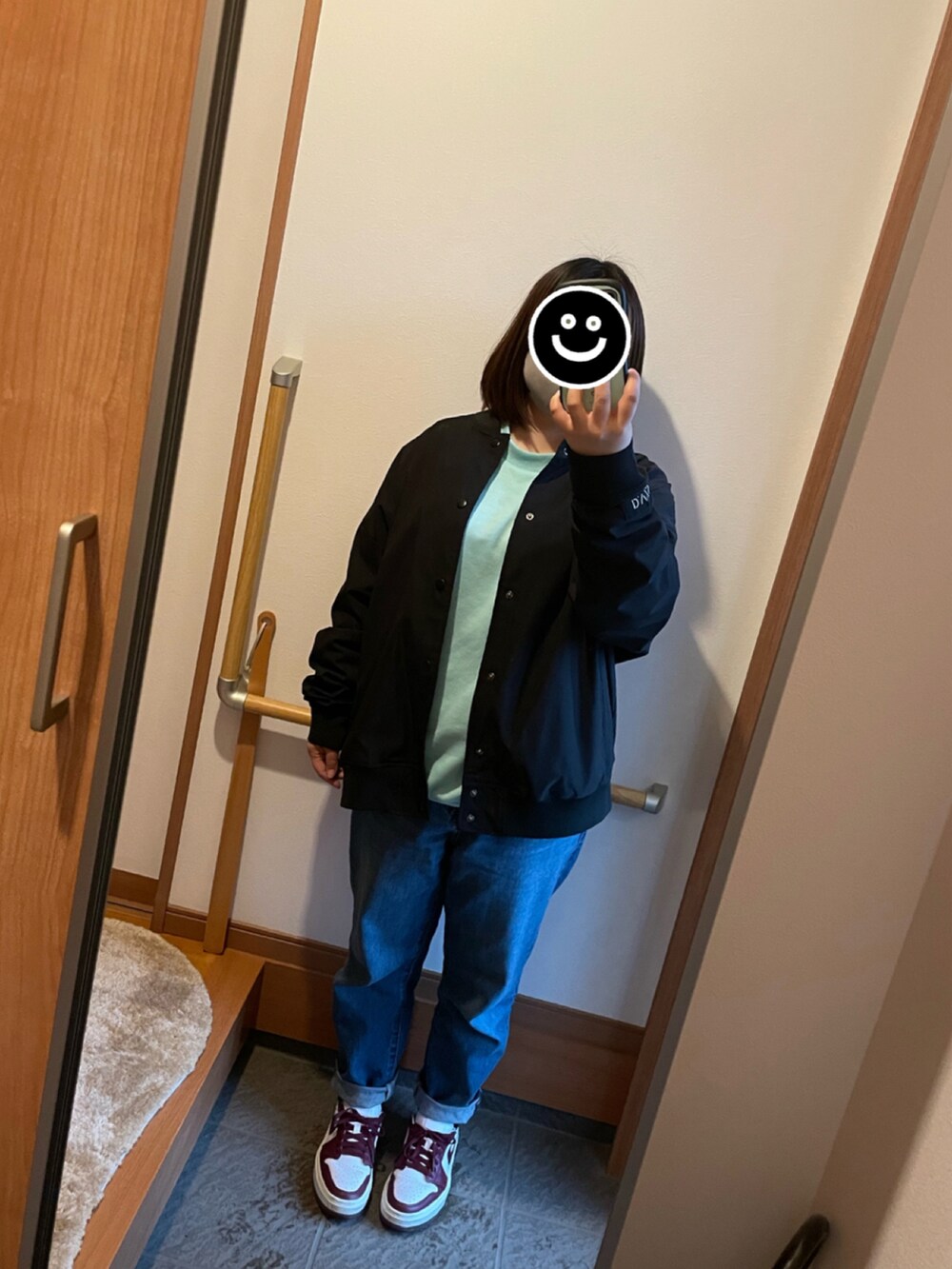 グリーン系のスウェット、ブルー系のデニムパンツ、ホワイト系のスニーカーを着用したレディースの春コーディネートの2枚目の写真