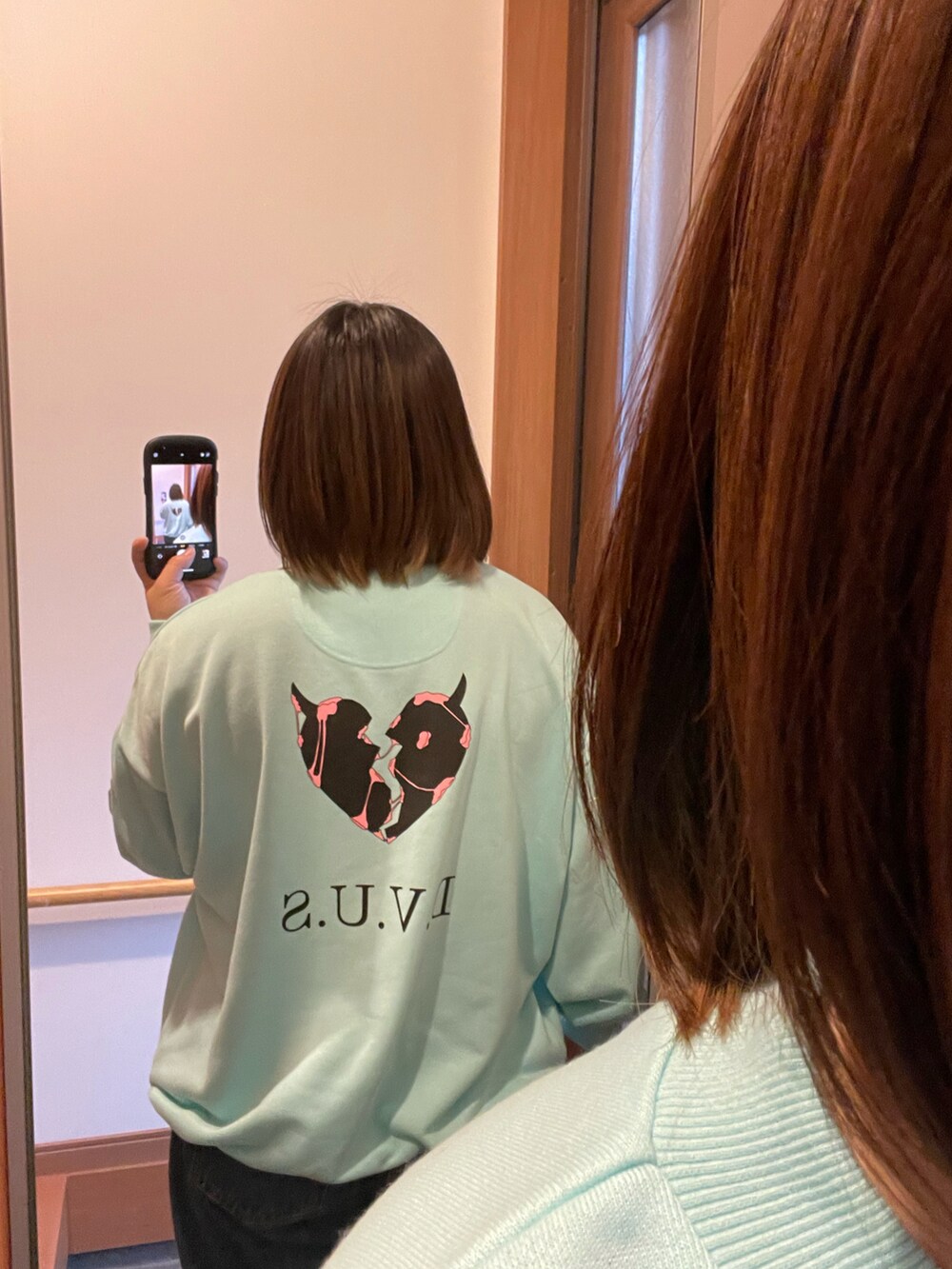 グリーン系のスウェット、ブルー系のデニムパンツ、ホワイト系のスニーカーを着用したレディースの春コーディネートの3枚目の写真