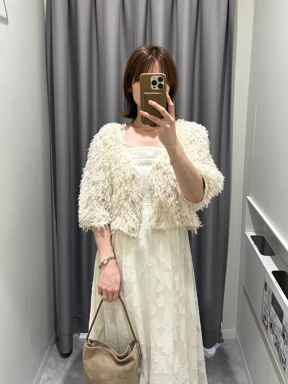 ホワイト系のワンピース、ホワイト系のカーディガン/ボレロ、ベージュ系のハンドバッグを着用したレディースの秋コーディネートの2枚目の写真