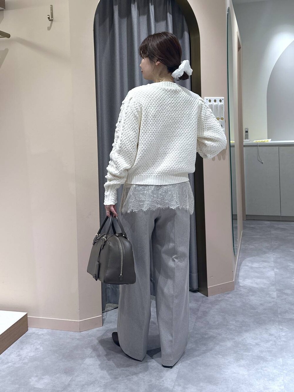 ブラウン系のハンドバッグ、ブラウン系のブーツ、ベージュ系のスラックスを着用したレディースの冬コーディネートの3枚目の写真