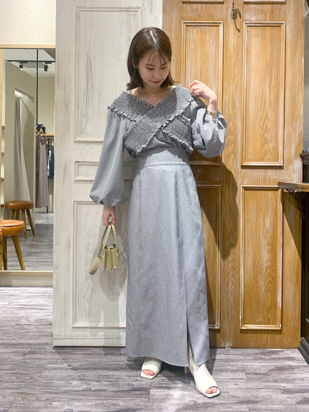 ブラック系のシャツ/ブラウス、グレー系のスカート、ホワイト系のブーツを着用したレディースの春コーディネートの2枚目の写真