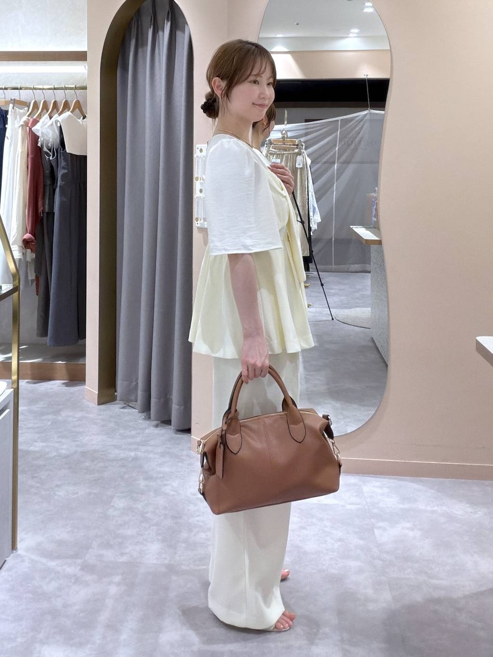 ブラウン系のボストンバッグ、ホワイト系のサンダル、ホワイト系のスラックスを着用したレディースの夏コーディネートの2枚目の写真