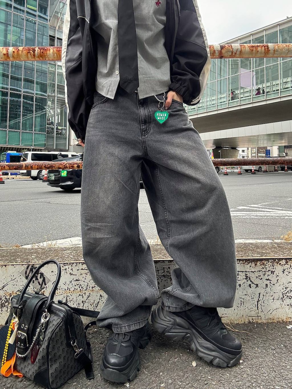 ブラック系のスニーカー、ブラック系のボストンバッグ、ブラック系のデニムパンツを着用したレディースの春コーディネートの5枚目の写真