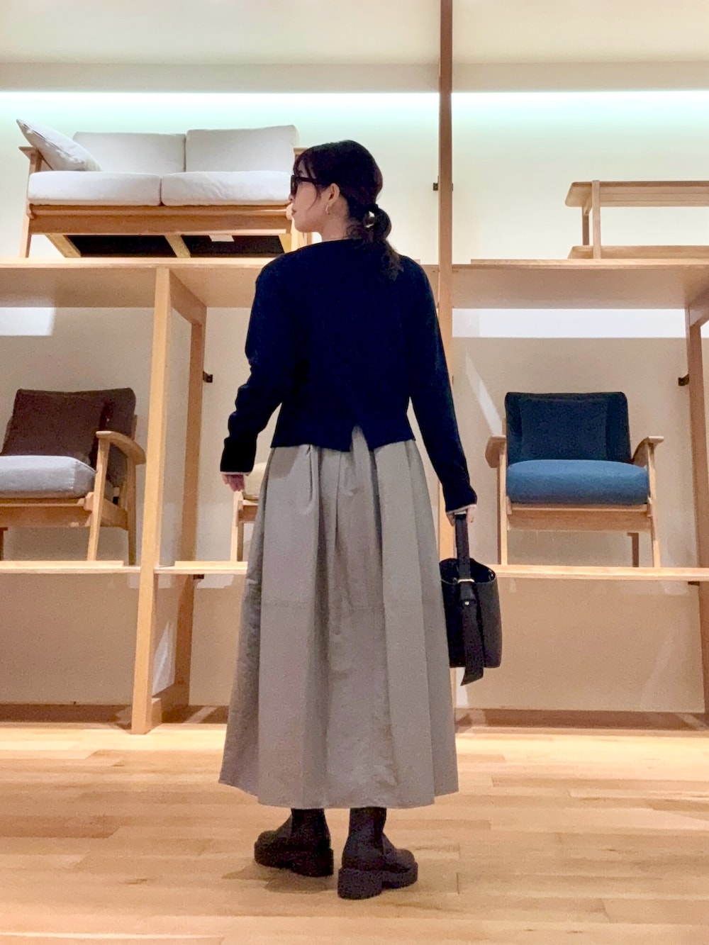 ブラック系のピーコート、ブラック系のハンドバッグ、ブルー系のニット/セーターを着用したレディースの冬コーディネートの8枚目の写真