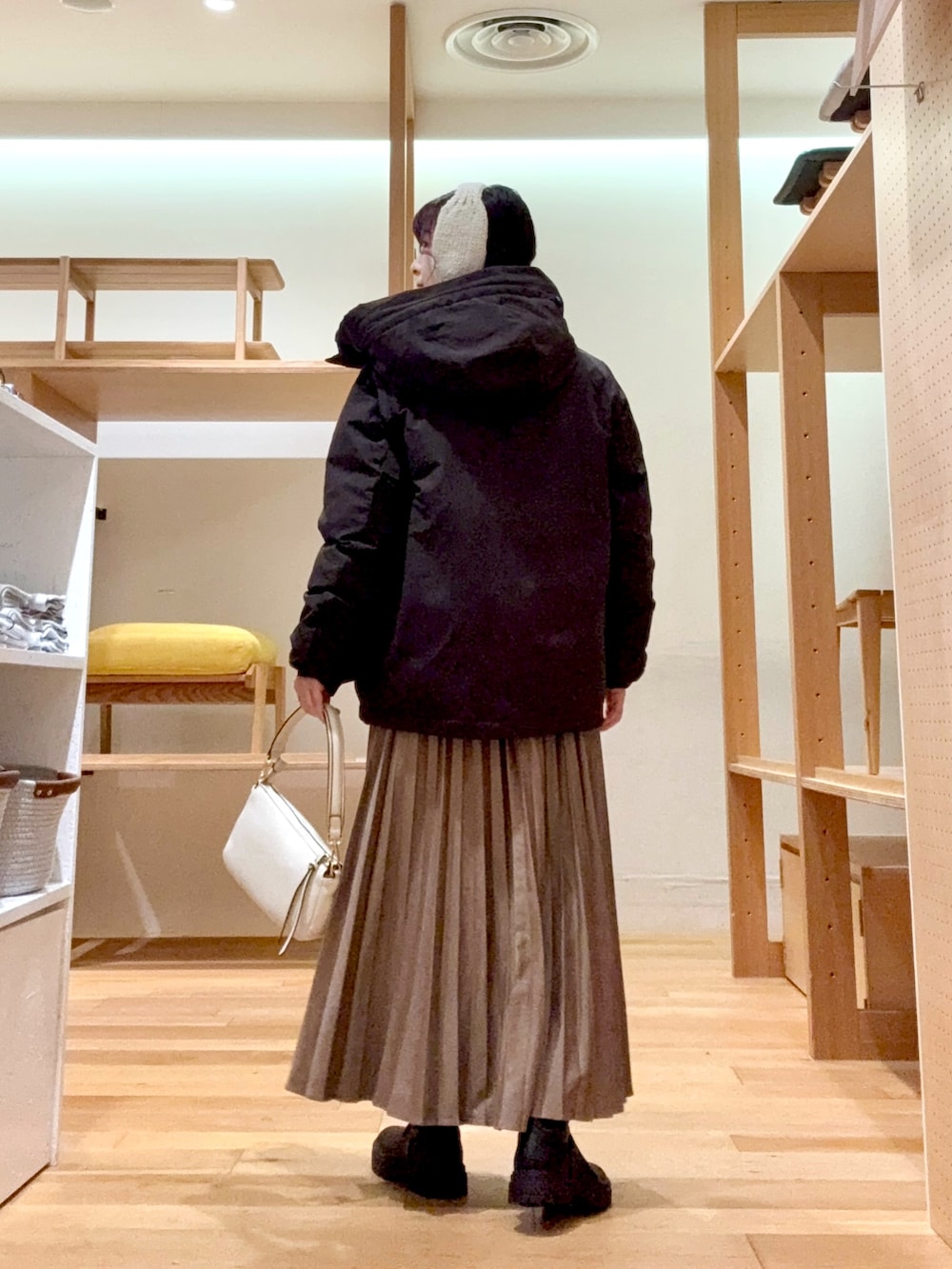 ブラウン系のダウンジャケット/コート、ホワイト系のTシャツ/カットソー、イエロー系のカーディガン/ボレロを着用したレディースの冬コーディネートの4枚目の写真