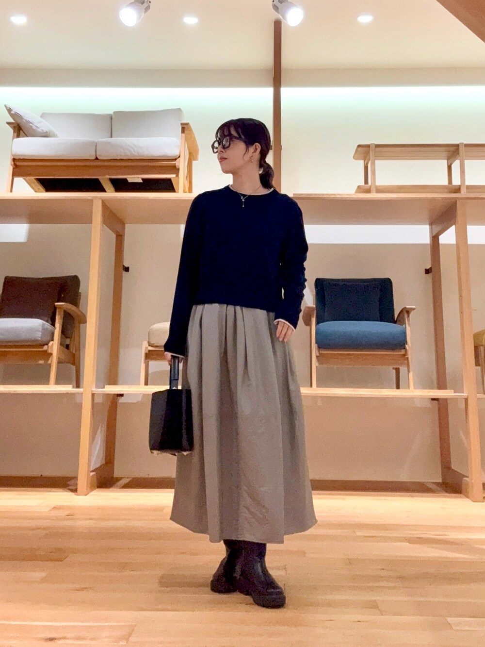 ブラック系のピーコート、ブラック系のハンドバッグ、ブルー系のニット/セーターを着用したレディースの冬コーディネートの7枚目の写真