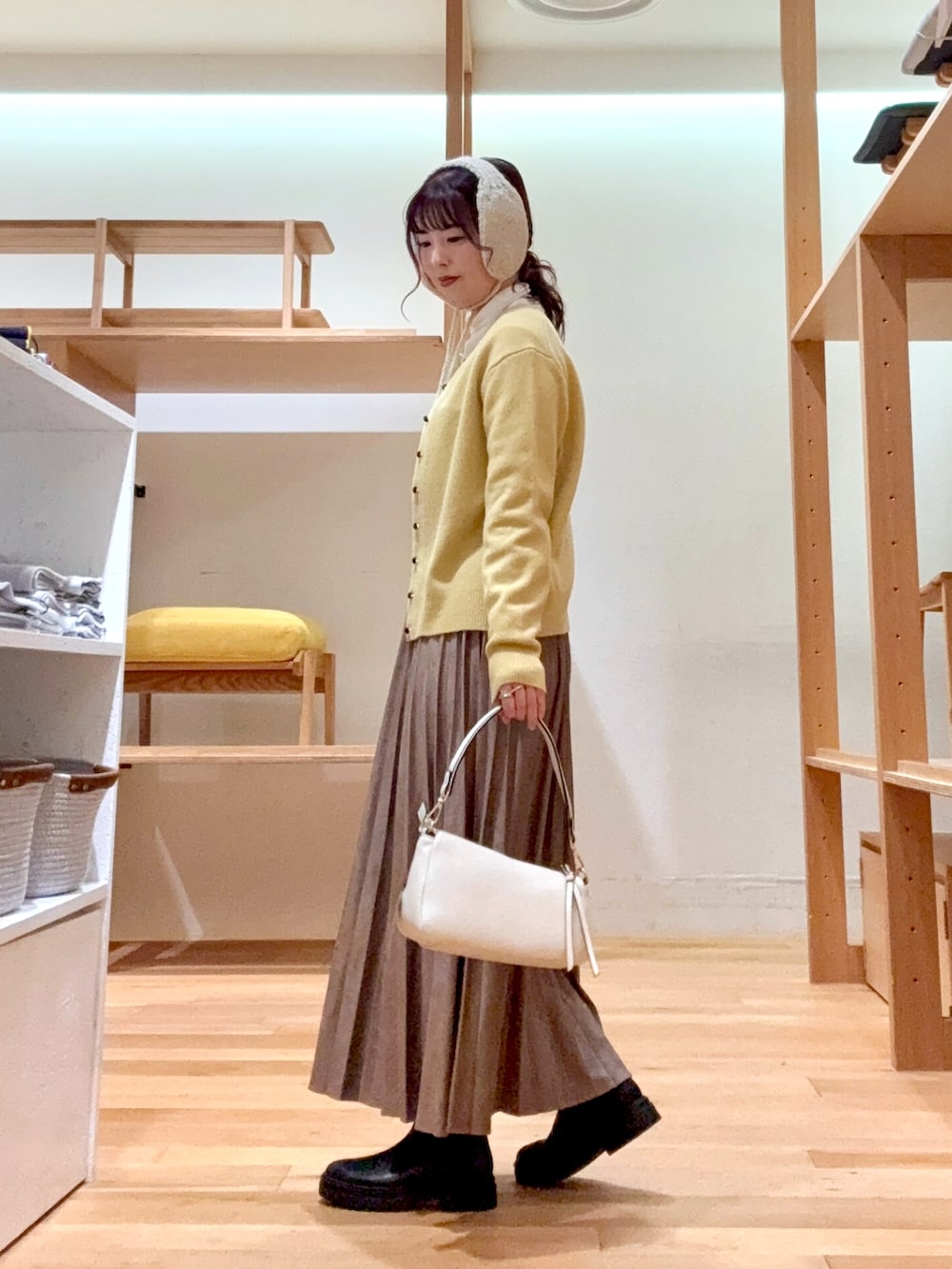 ブラウン系のダウンジャケット/コート、ホワイト系のTシャツ/カットソー、イエロー系のカーディガン/ボレロを着用したレディースの冬コーディネートの6枚目の写真