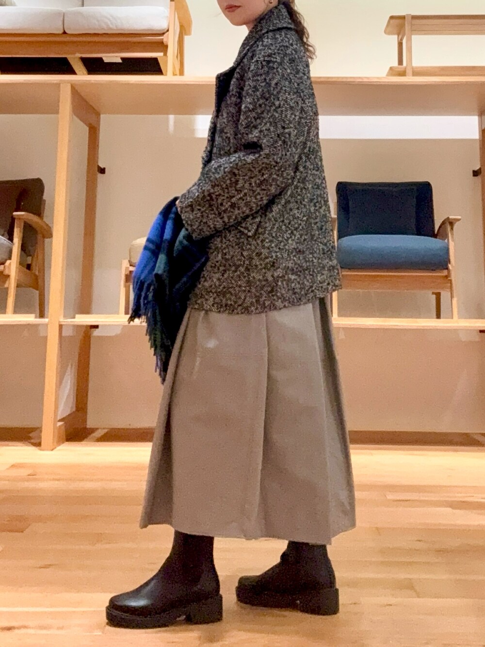 ブラック系のピーコート、ブラック系のハンドバッグ、ブルー系のニット/セーターを着用したレディースの冬コーディネートの3枚目の写真