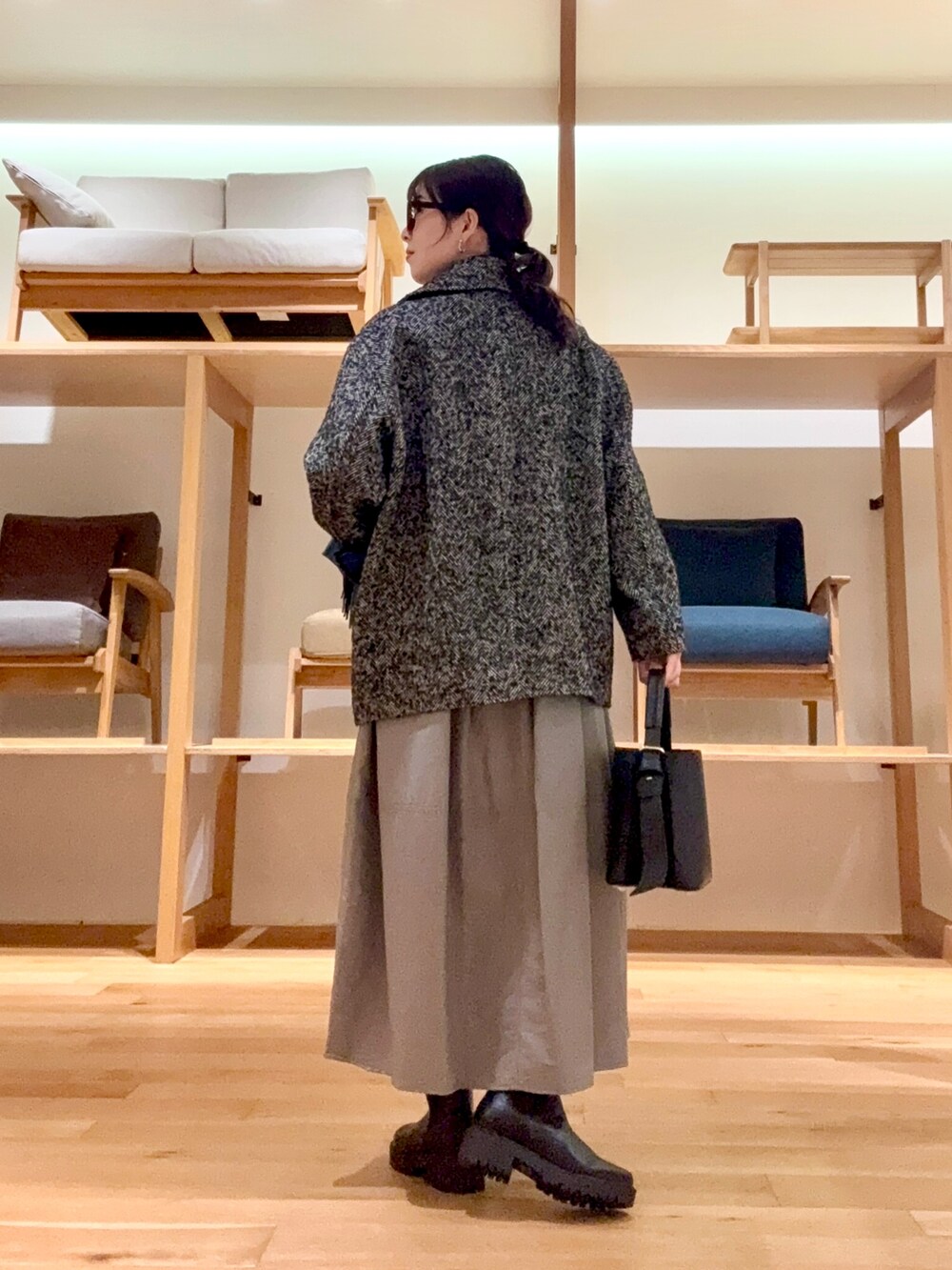 ブラック系のピーコート、ブラック系のハンドバッグ、ブルー系のニット/セーターを着用したレディースの冬コーディネートの4枚目の写真