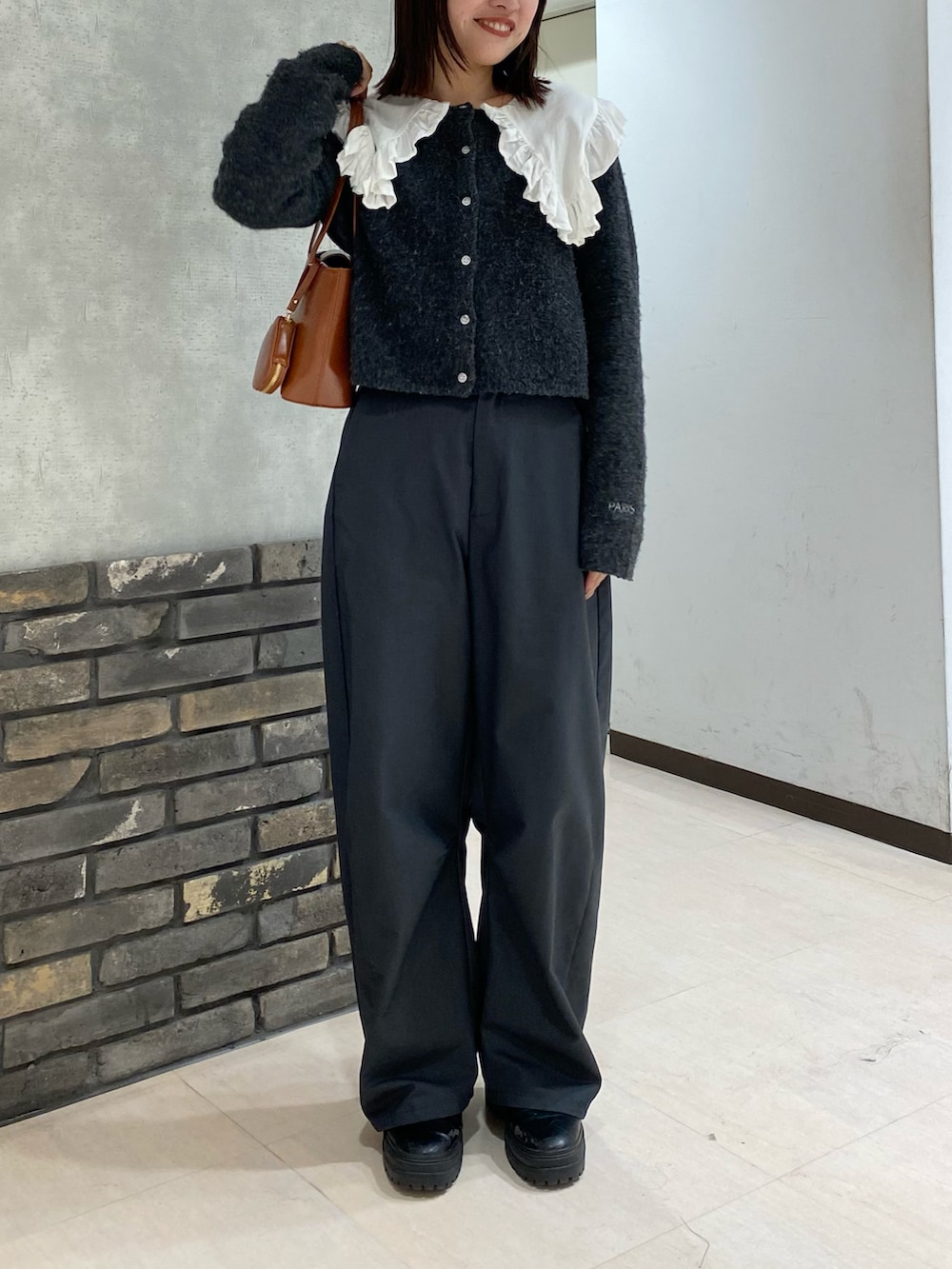 グレー系のカーディガン/ボレロ、ホワイト系のシャツ/ブラウス、ブラウン系のハンドバッグを着用したレディースの冬コーディネートの3枚目の写真