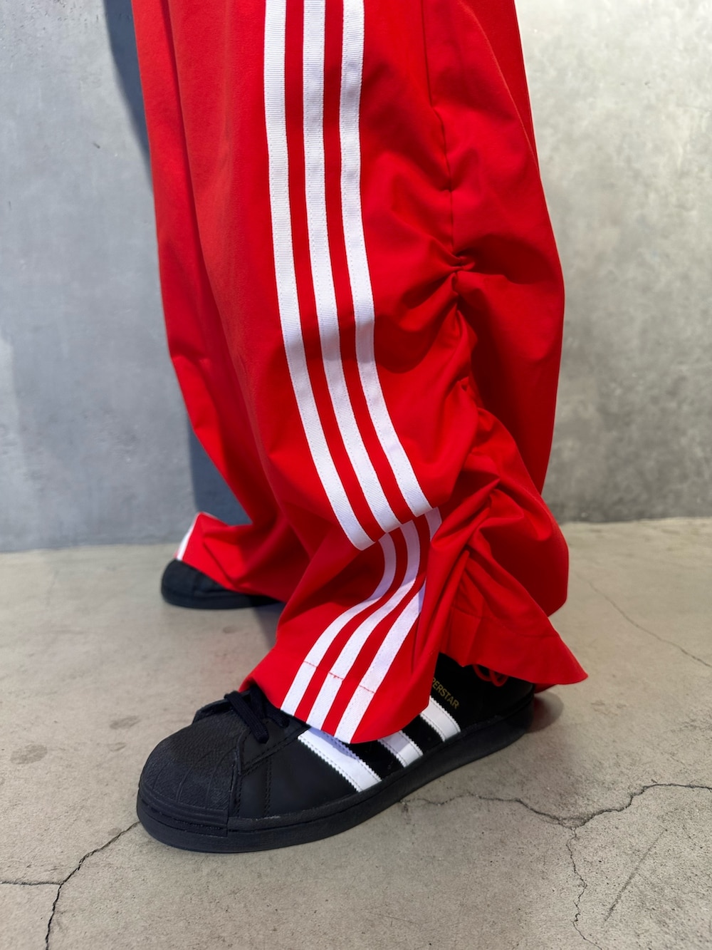 レッド系のトップス、ブラック系のスウェットパンツ、ブラック系のシューズを着用したメンズの秋コーディネートの2枚目の写真