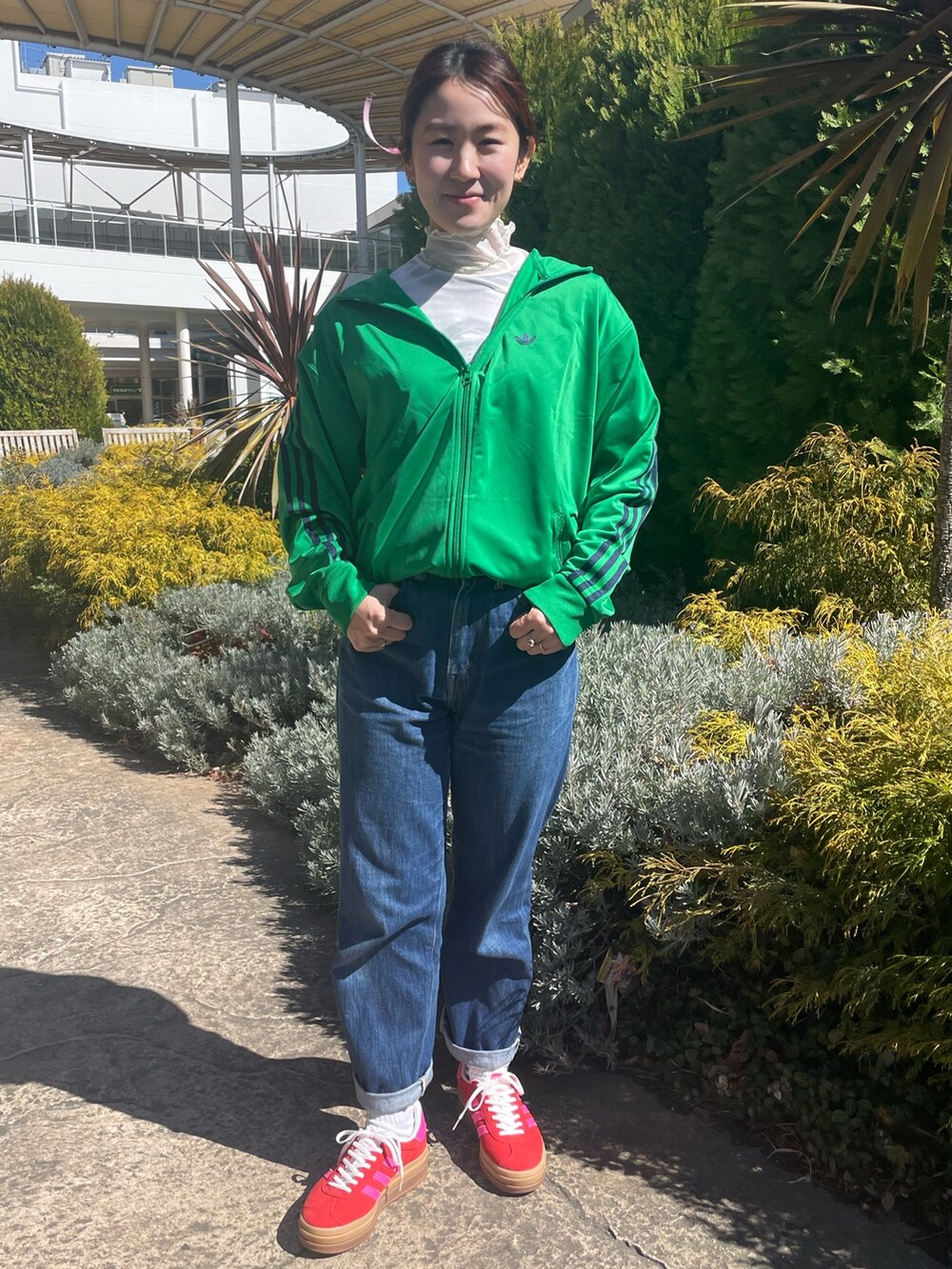 グリーン系のジャージ、レッド系のスニーカーを着用したレディースの春コーディネートの2枚目の写真