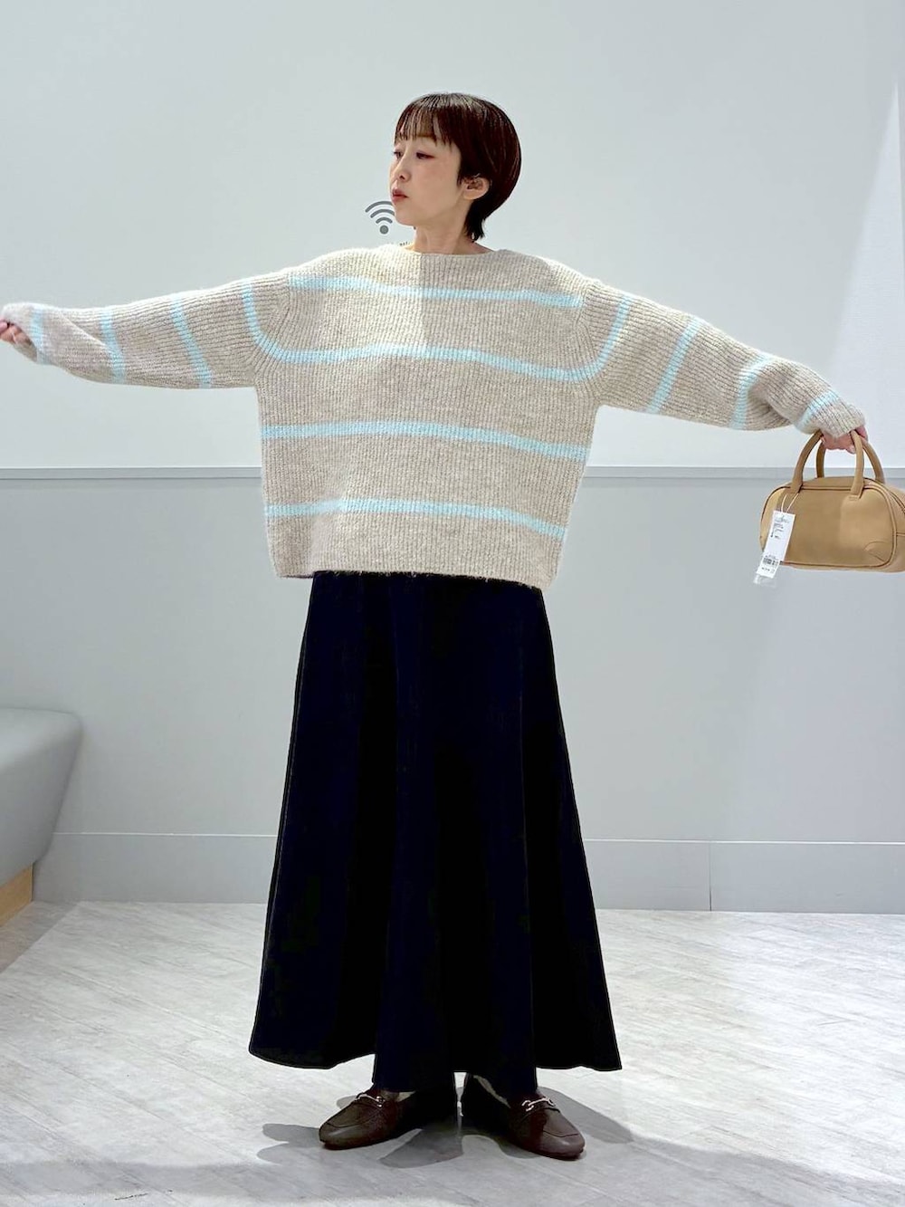 ベージュ系のローファー、グレー系のスカート、ブラウン系のハンドバッグを着用したレディースの秋コーディネートの3枚目の写真